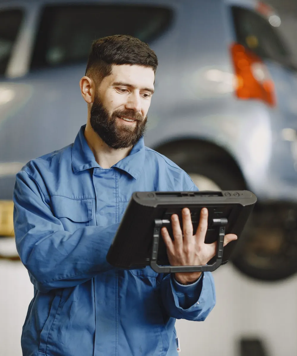 Meccanico con il tablet di diagnosi sotto un'auto sollevata sul ponte